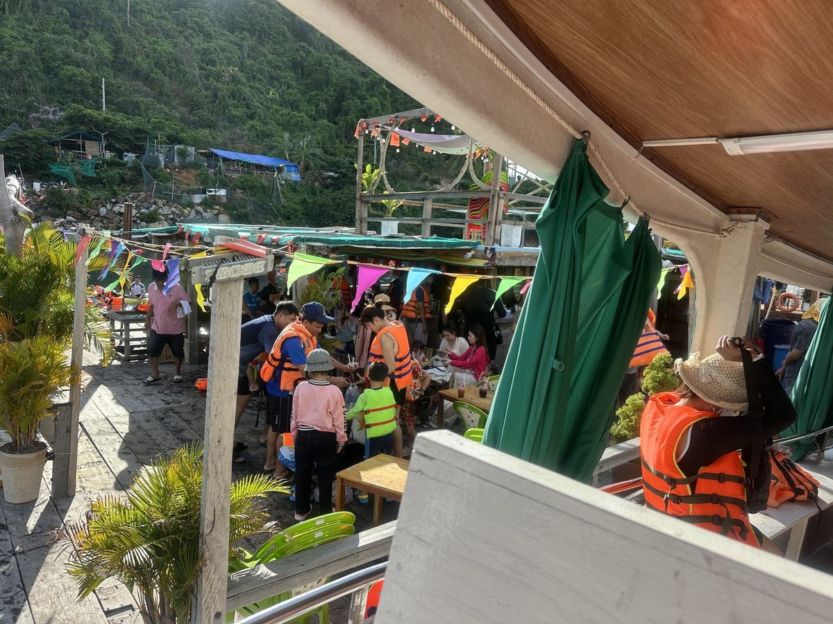 Khách mặc áo phao đứng trên sàn bè nổi ở làng bè Hòn Sơn