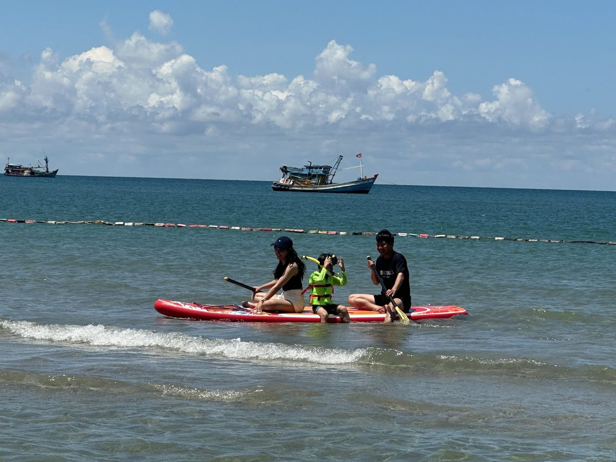 Khách chèo SUP ngoài khơi Bãi Bàng, đảo Hòn Sơn, phía sau là ghe cá của người đảo