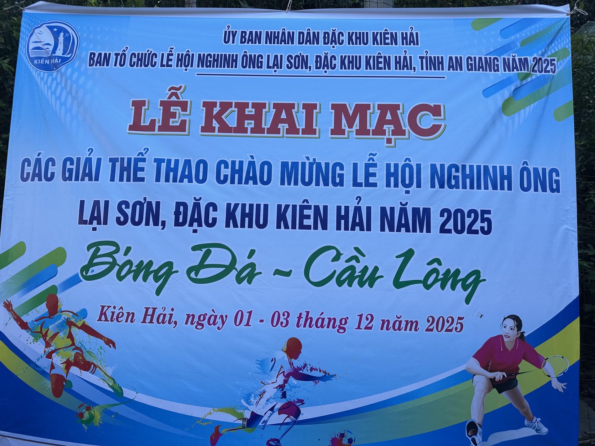 Băng rôn nền xanh của ban tổ chức ghi lễ khai mạc các giải thể thao chào mừng lễ hội Nghinh Ông Lại Sơn năm 2025, môn bóng đá và cầu lông, Kiên Hải ngày 01 tới 03 tháng 12 năm 2025